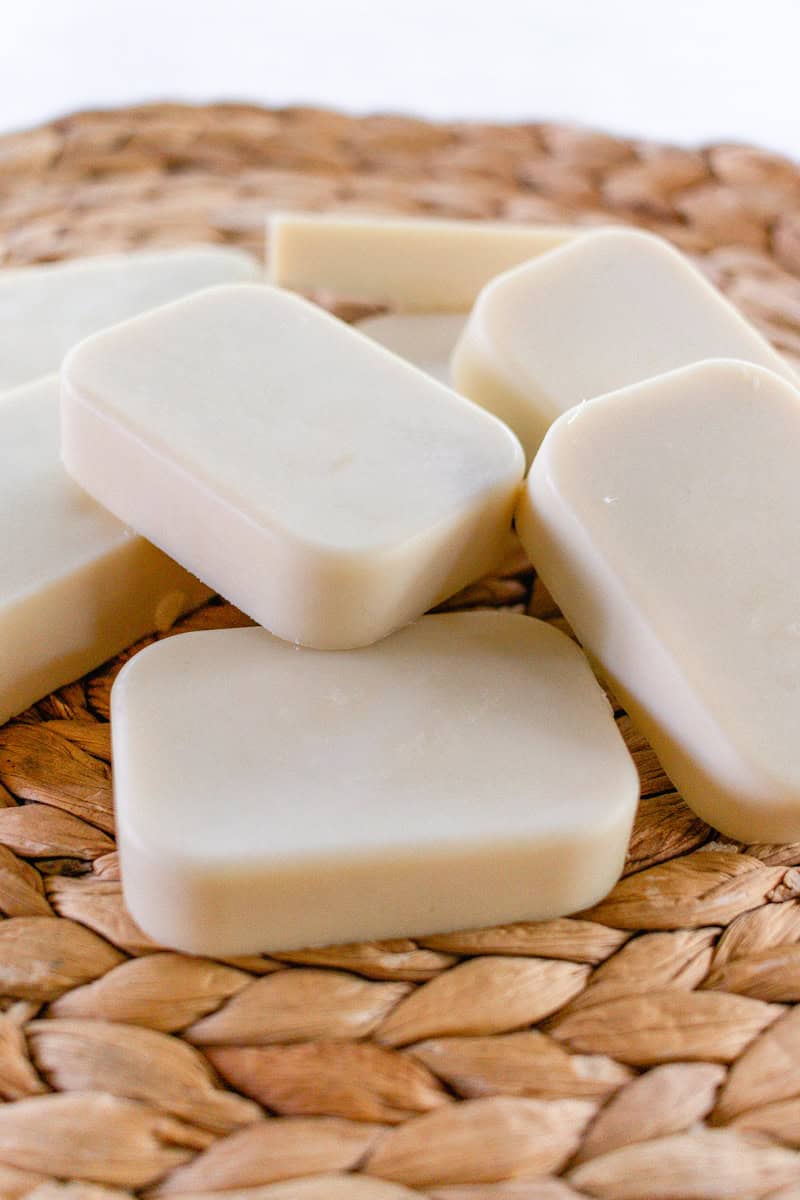 White rectangular soap bars stacked on a woven placemat. 