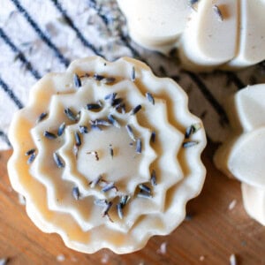 Three flower-shaped bars of lard soap on a wooden countertop.