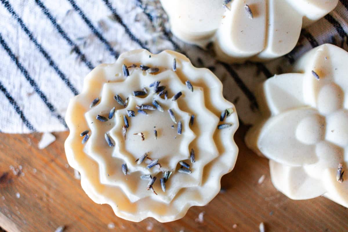 Three flower-shaped bars of lard soap on a wooden countertop.