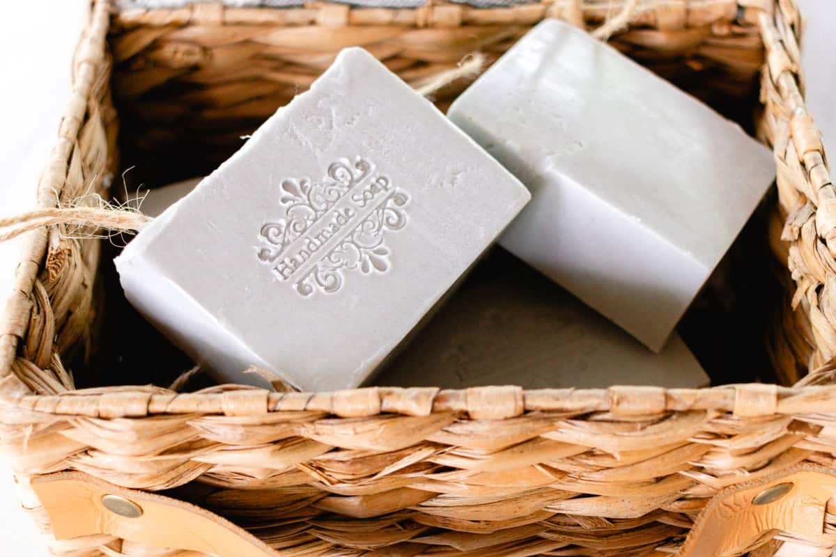 Soap on a rope bars sitting in a wicker basket. The soap bars are stamped with "handmade soap."