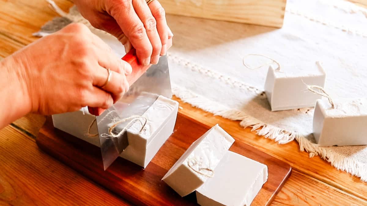 Cutting the finished soap loaf into individual soap bars with a soap cutter. 