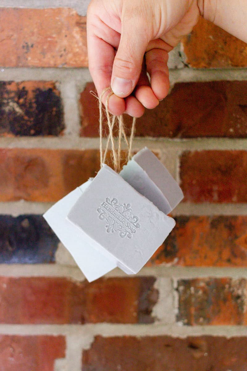 A hand holding three soap on a rope bars by the jute string handles. 