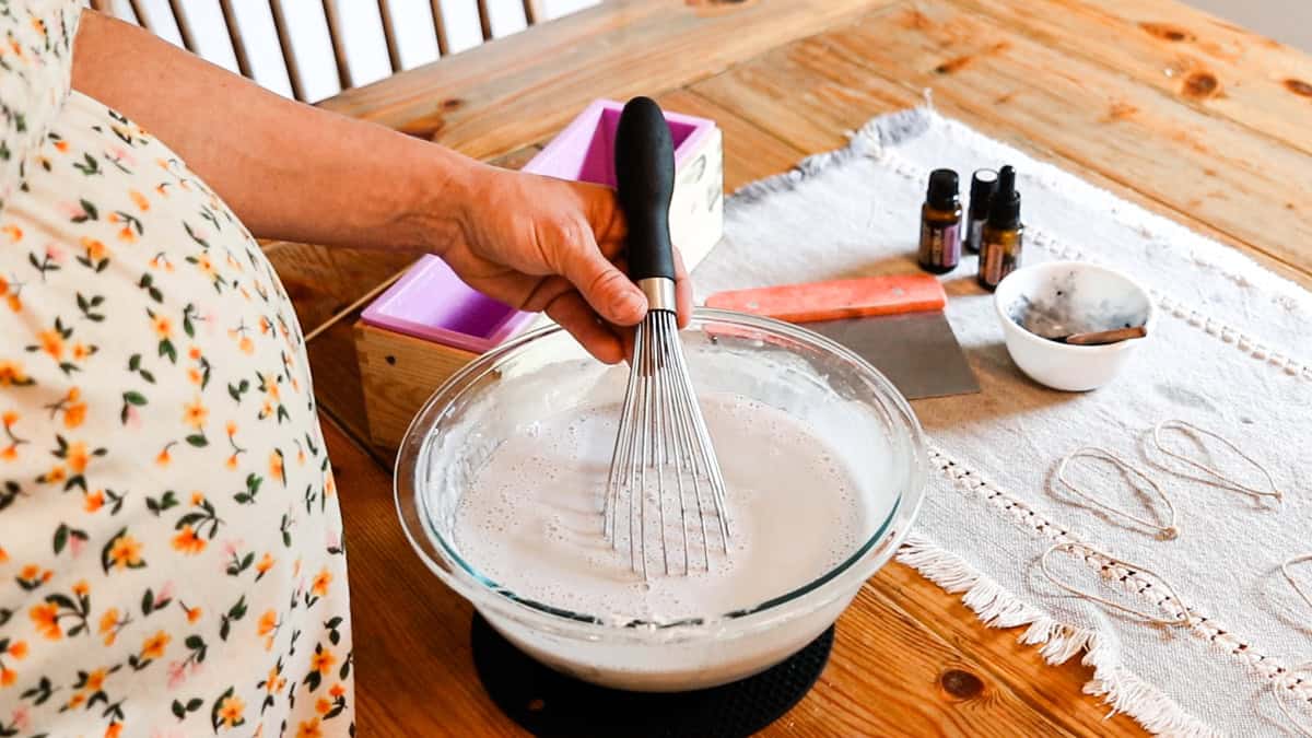 Using a whisk to stir the activated charcoal into the soap base. 
