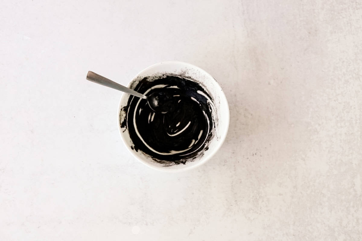 DIY eyebrow tint in a small white bowl with a spoon in it. 