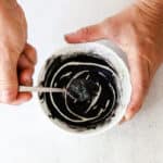 Stirring DIY eyebrow tint in a small bowl to form a thick paste.