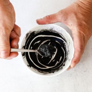 Stirring DIY eyebrow tint in a small bowl to form a thick paste.