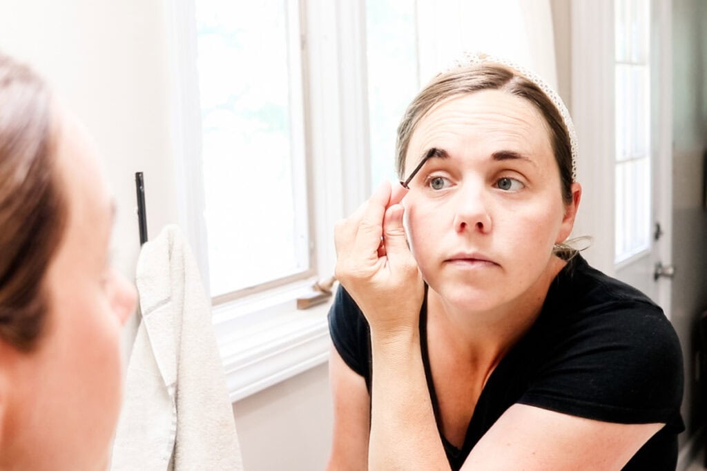 Applying the eyebrow tint to my eyebrows with an applicator brush. 