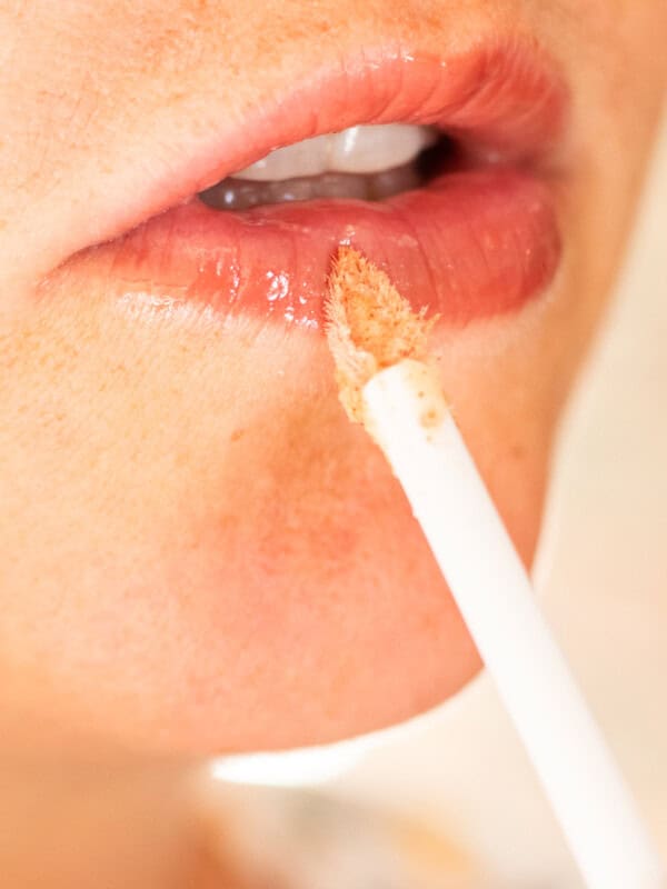 Applying homemade lip plumper onto my lips with an applicator.