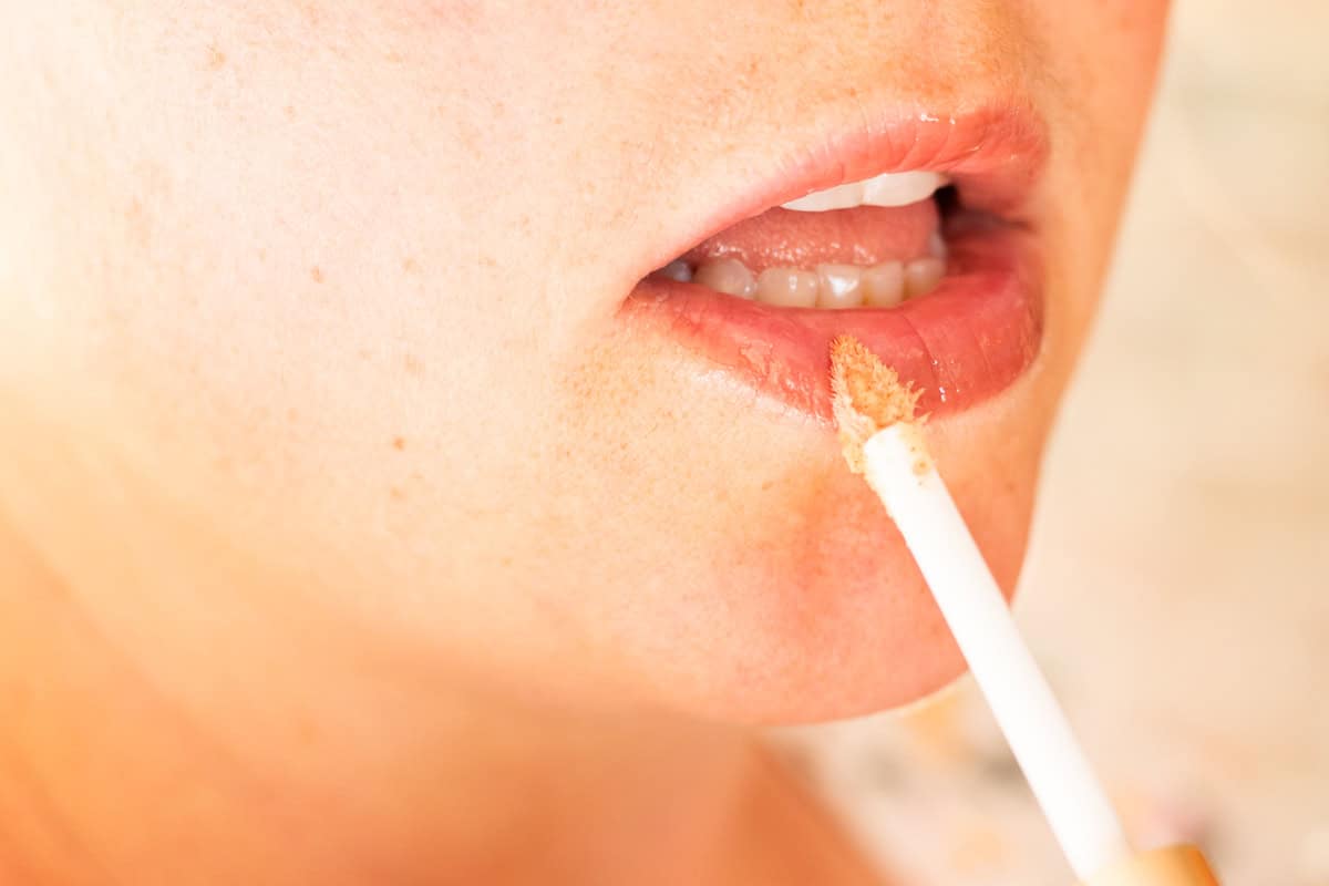 Applying lip plumper with a lip product brush applicator. 