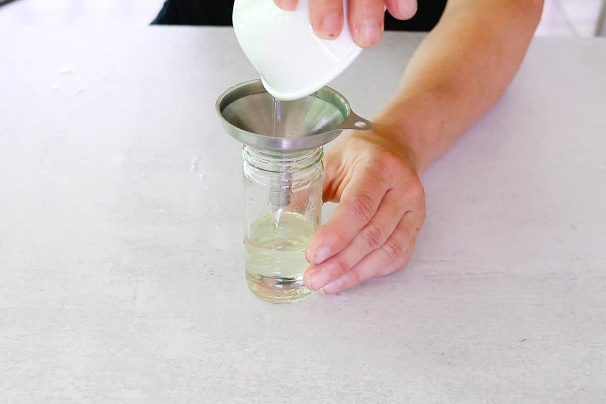 Pouring aloe vera into a glass beaker to make eye serum. 