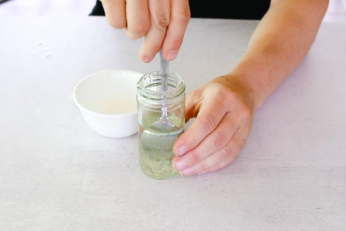 Stirring the aloe into the carrier oils with a spoon.