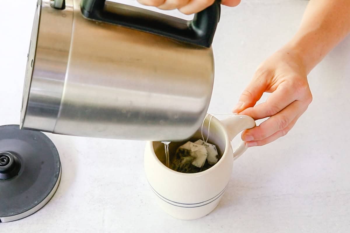Pouring water into a cup with a tea bag.