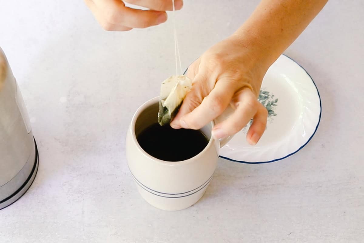 Squeezing out a tea bag over a cup of tea.
