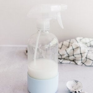 Homemade starch spray on a white marble laundry table.