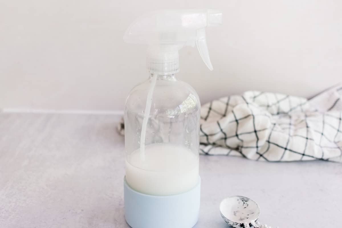 Homemade starch spray on a white marble laundry table.
