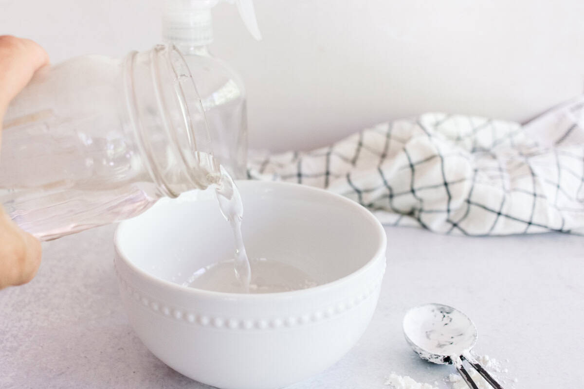 Pouring water into a bowl to make homemade spray starch. 