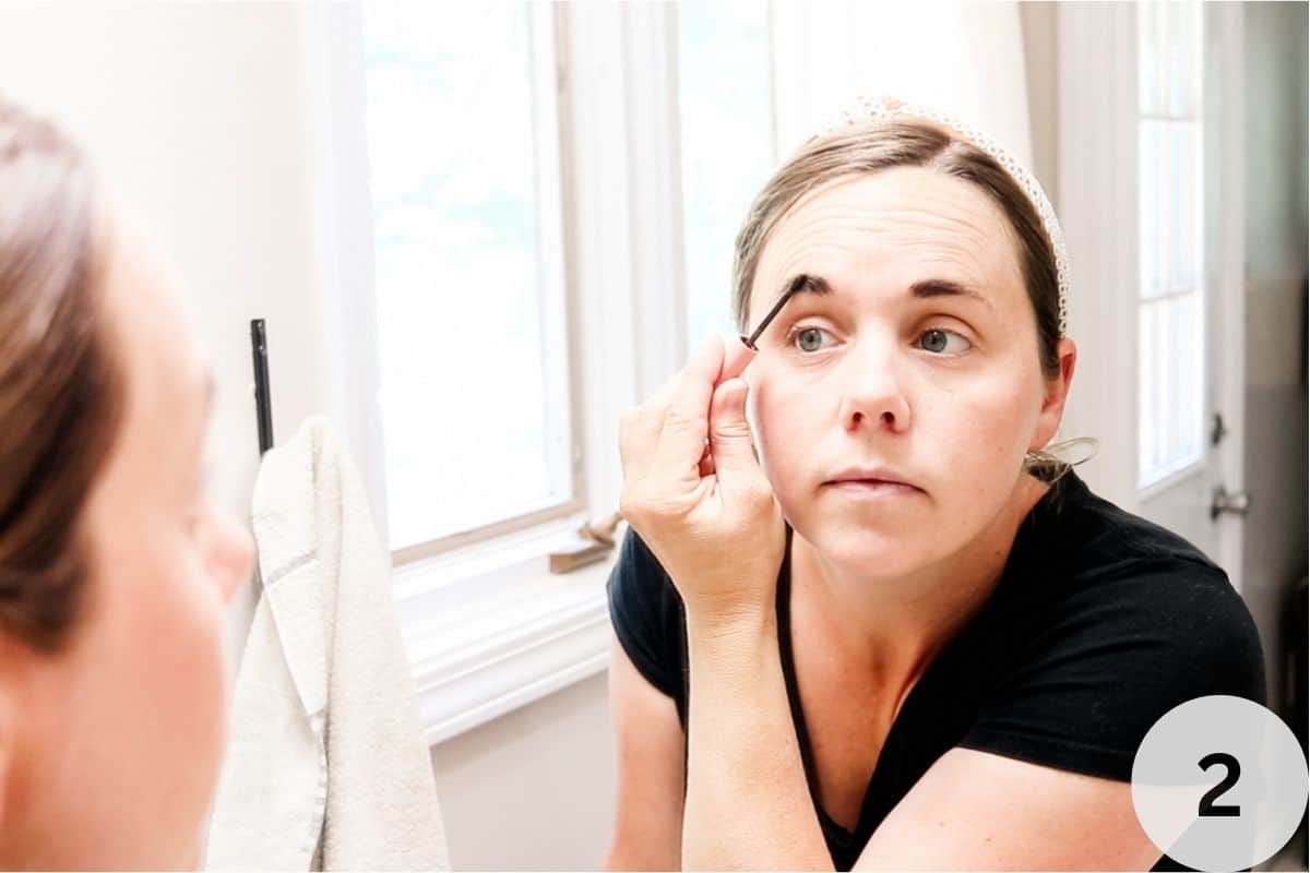 Applying the eyebrow tint to my eyebrows with an applicator brush.