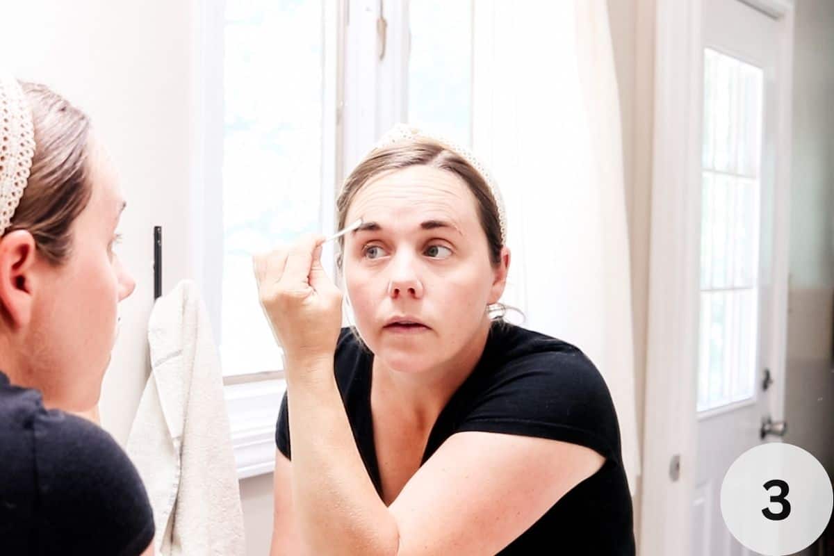 Using a q-tip to remove any excess tint around the brow area. 
