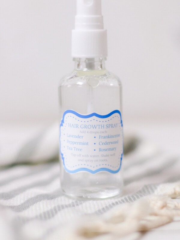 Hair growth spray with essential oils and water in the background.