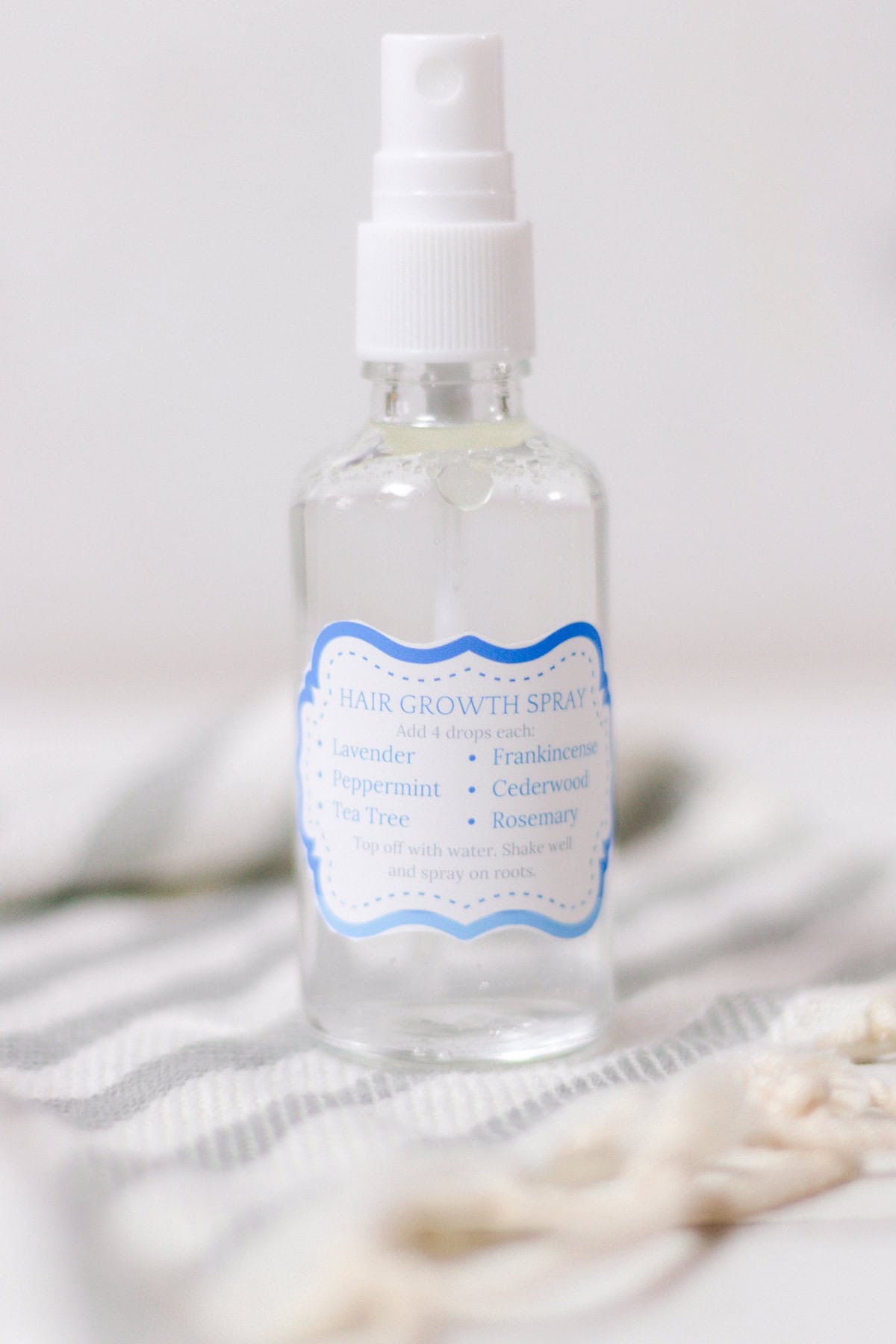 Hair growth spray with essential oils and water in the background.