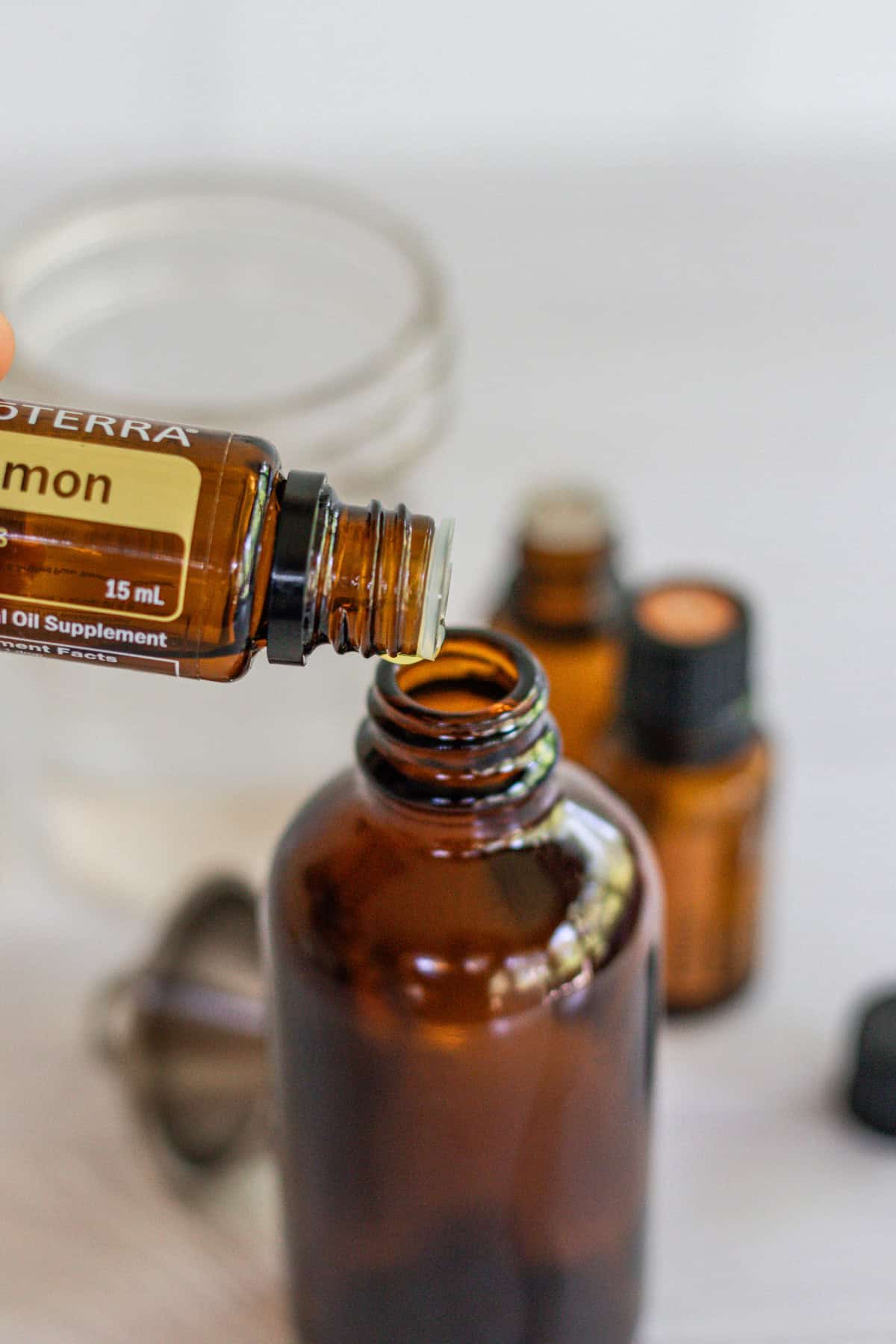 Dropping lemon essential oil into an amber glass spray bottle.