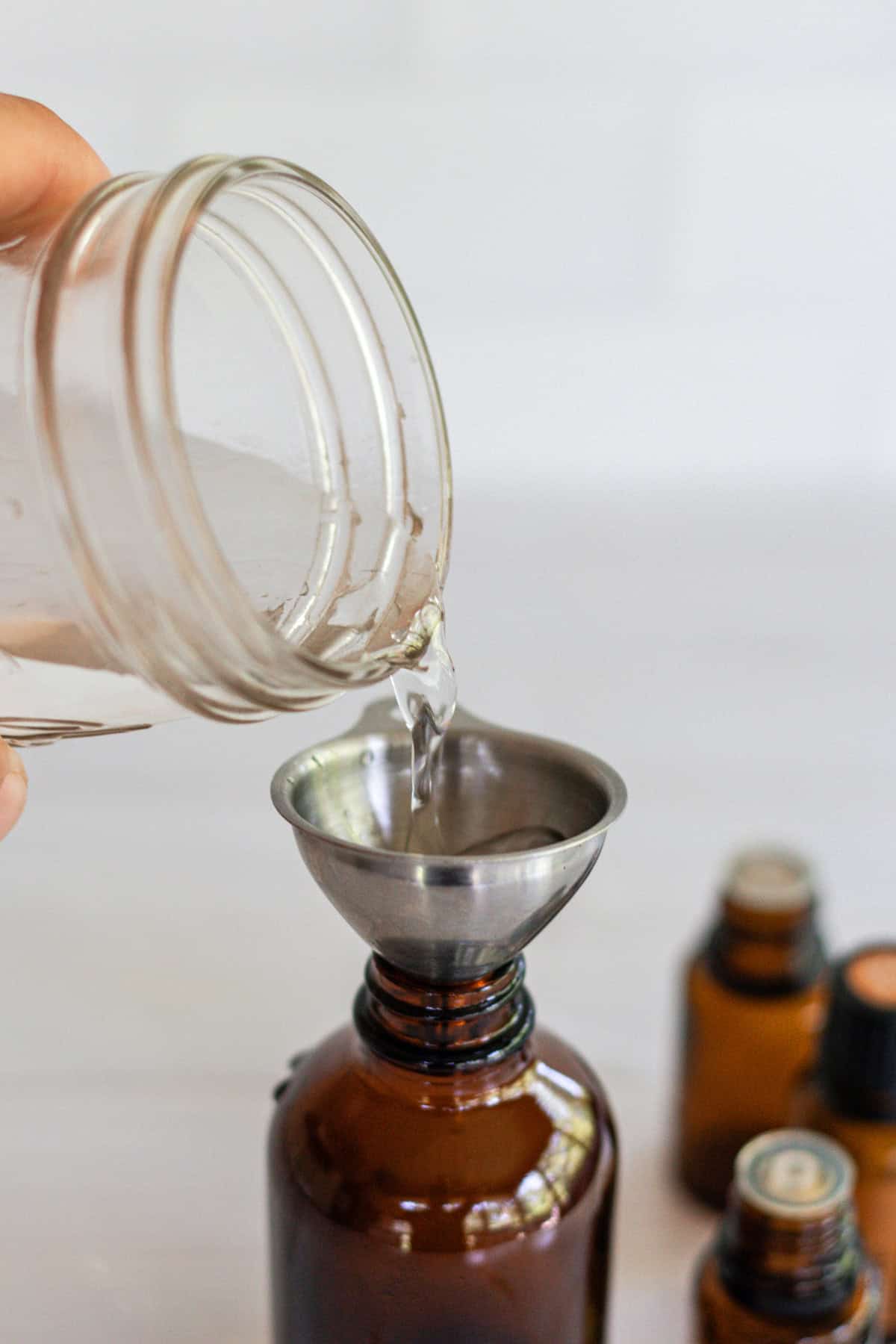 Pouring water into an amber glass bottle with a metal funnel.
