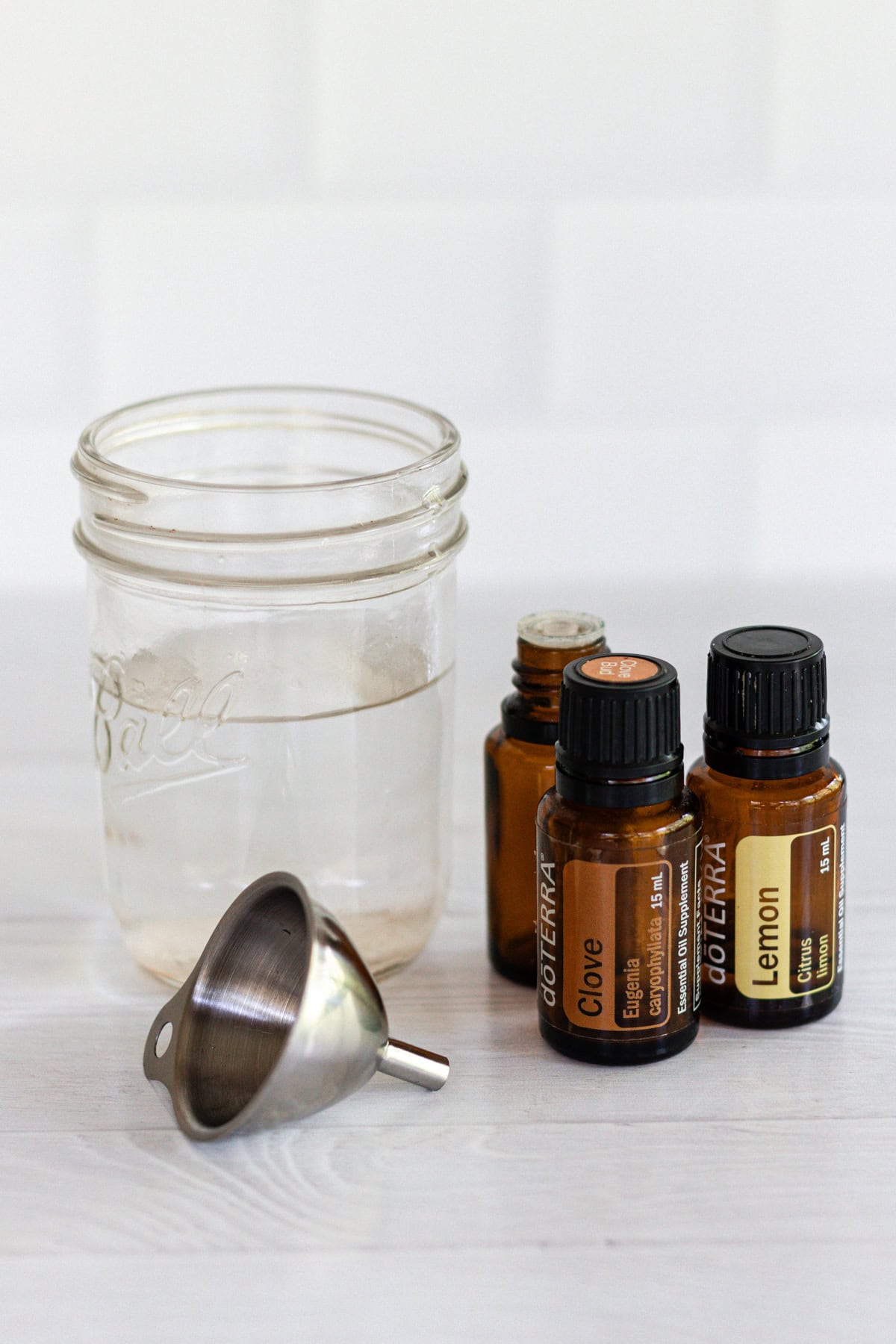 Ingredients for ant repellent: essential oils and water with a metal funnel.