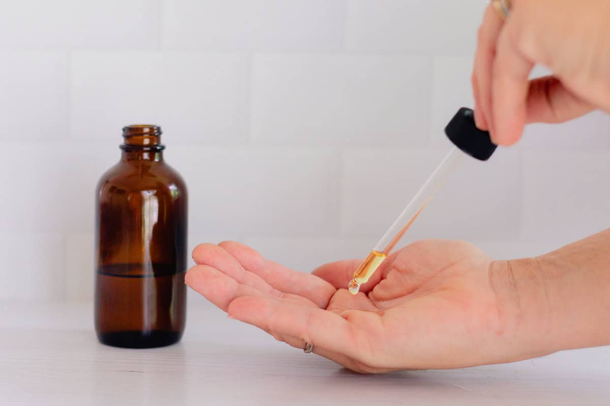 Dropping body oil into the palm to apply it to the skin.