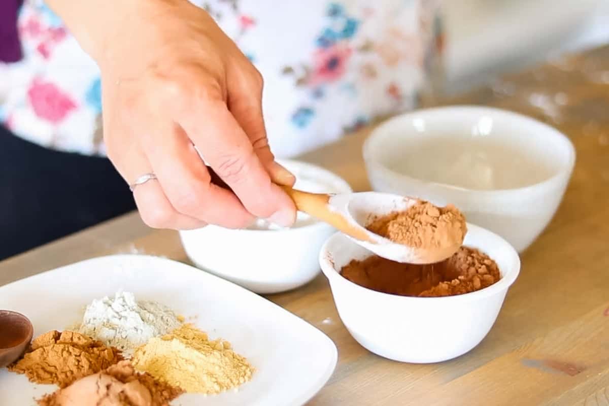 Scooping cocoa powder out of a bowl to make DIY foundation.