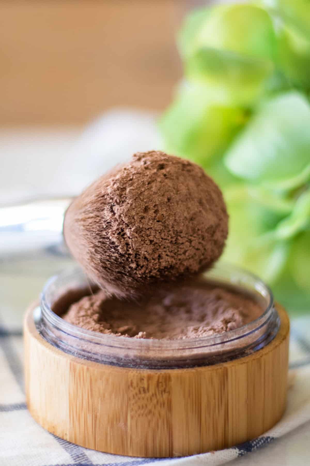 A makeup brush dipped in a container of homemade foundation.