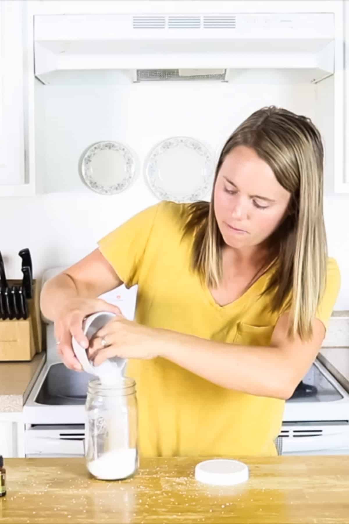 Adding laundry scent booster ingredients to a large mason jar.