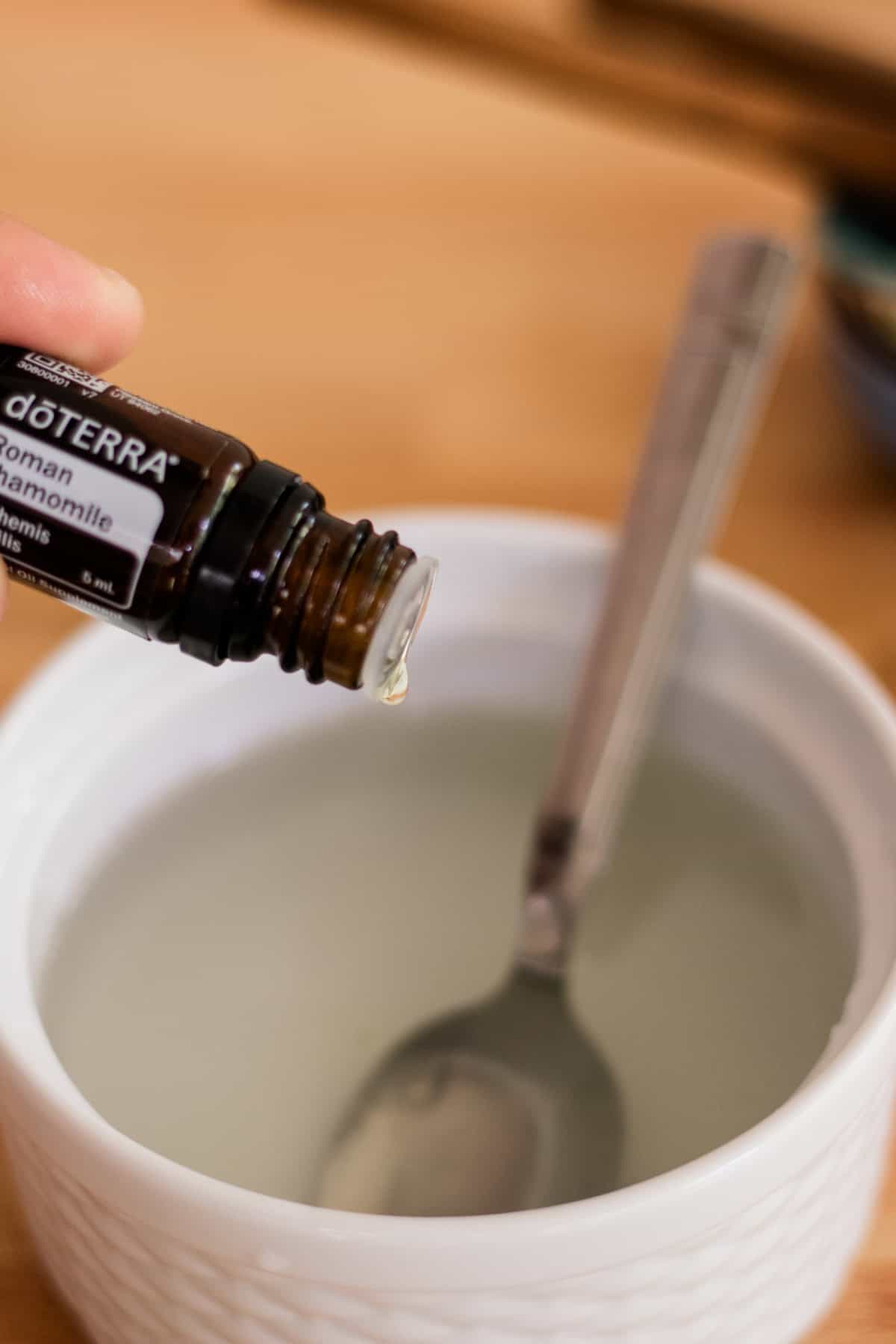 Dropping roman chamomile essential oils into a white bowl from an amber glass bottle.