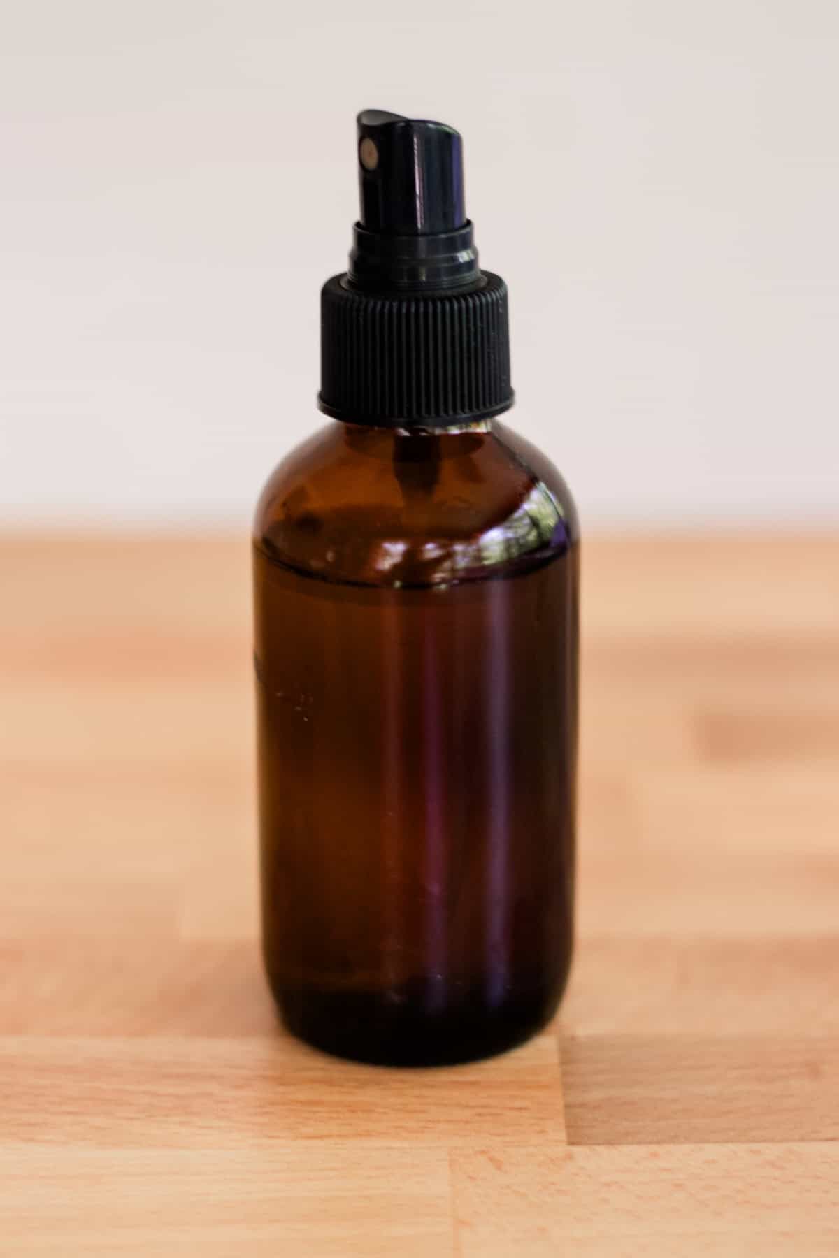 An amber glass spray bottle sitting on a countertop. 