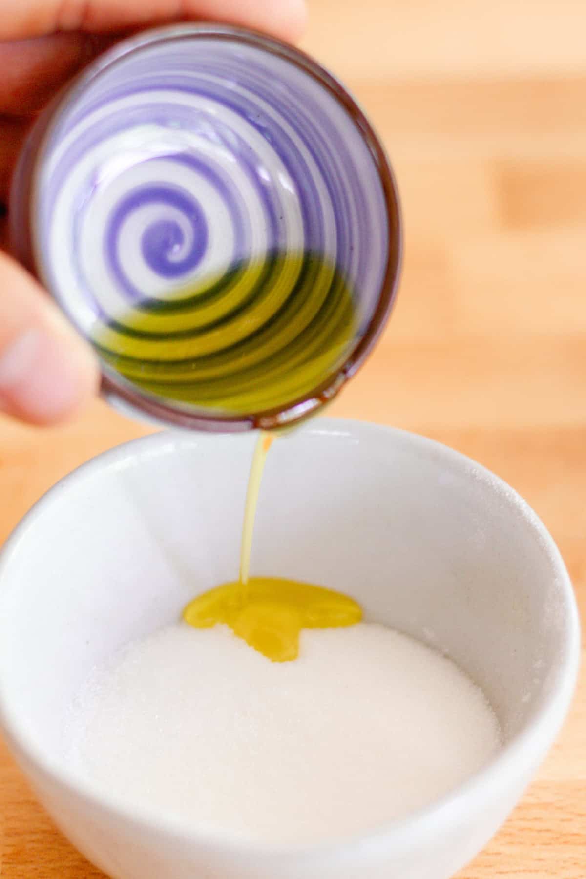 Pouring olive oil into a bowl of sugar.