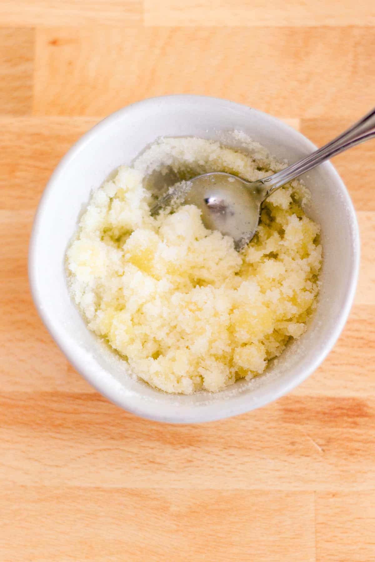 A bowl of olive oil and sugar stirred together with a spoon sticking out of it. 