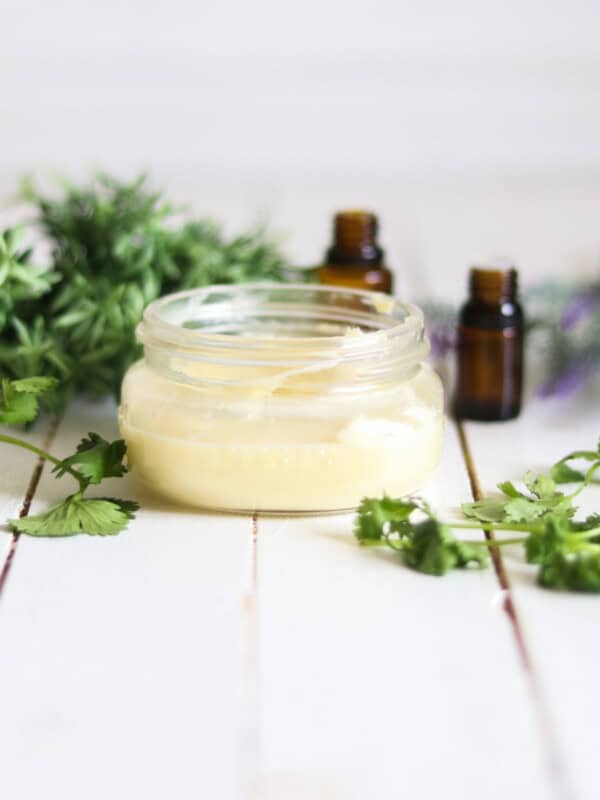 Homemade whipped body butter with lavender sprigs and essential oil bottles.