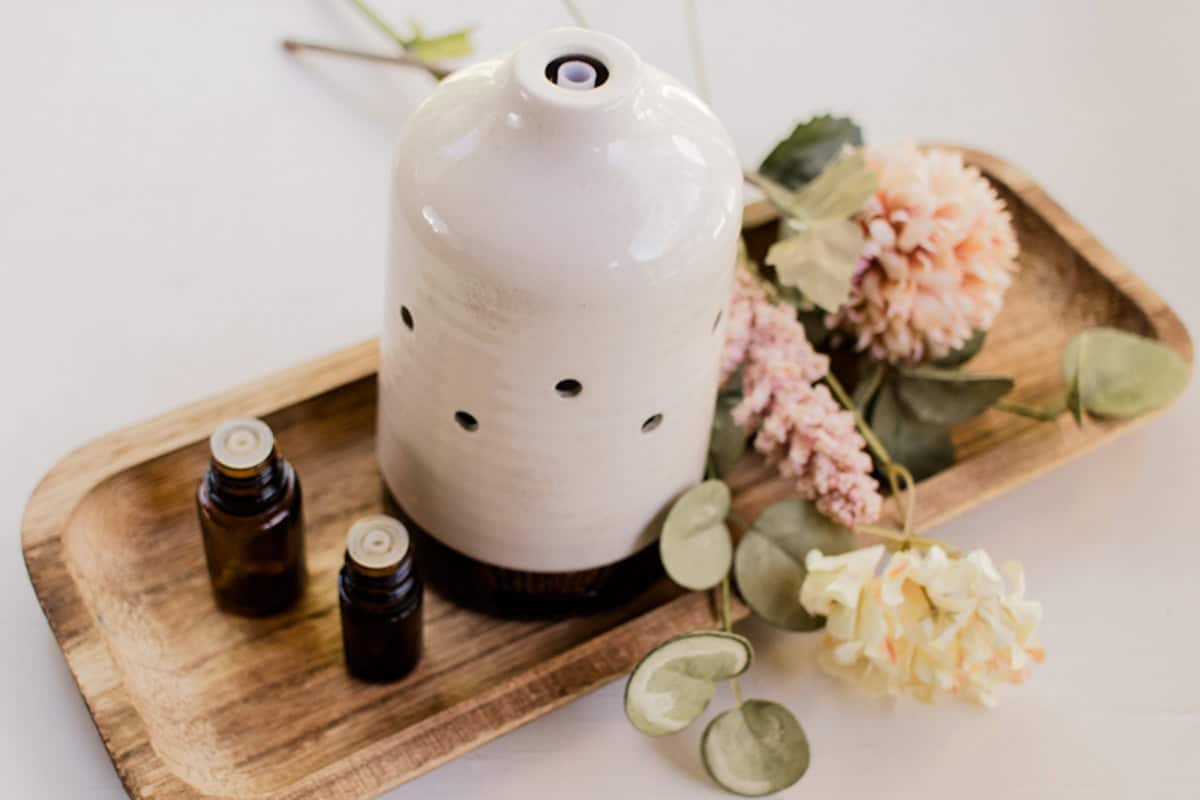 A small aromatherapy diffuser with several essential oils surrounding it. 