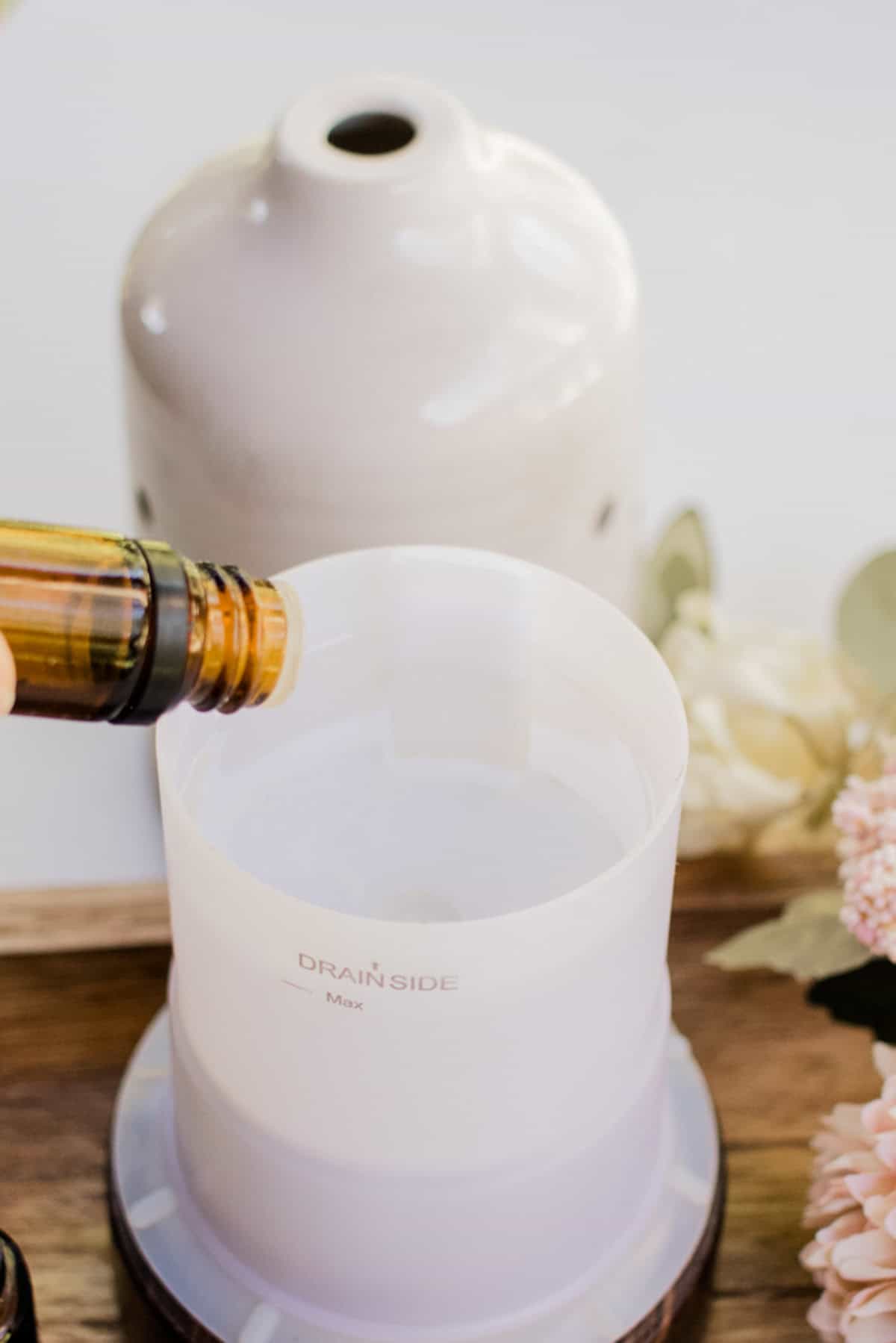 Adding essential oils to the diffuser reservoir. 