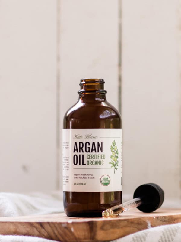 Bottle of argan oil on a wooden shelf.