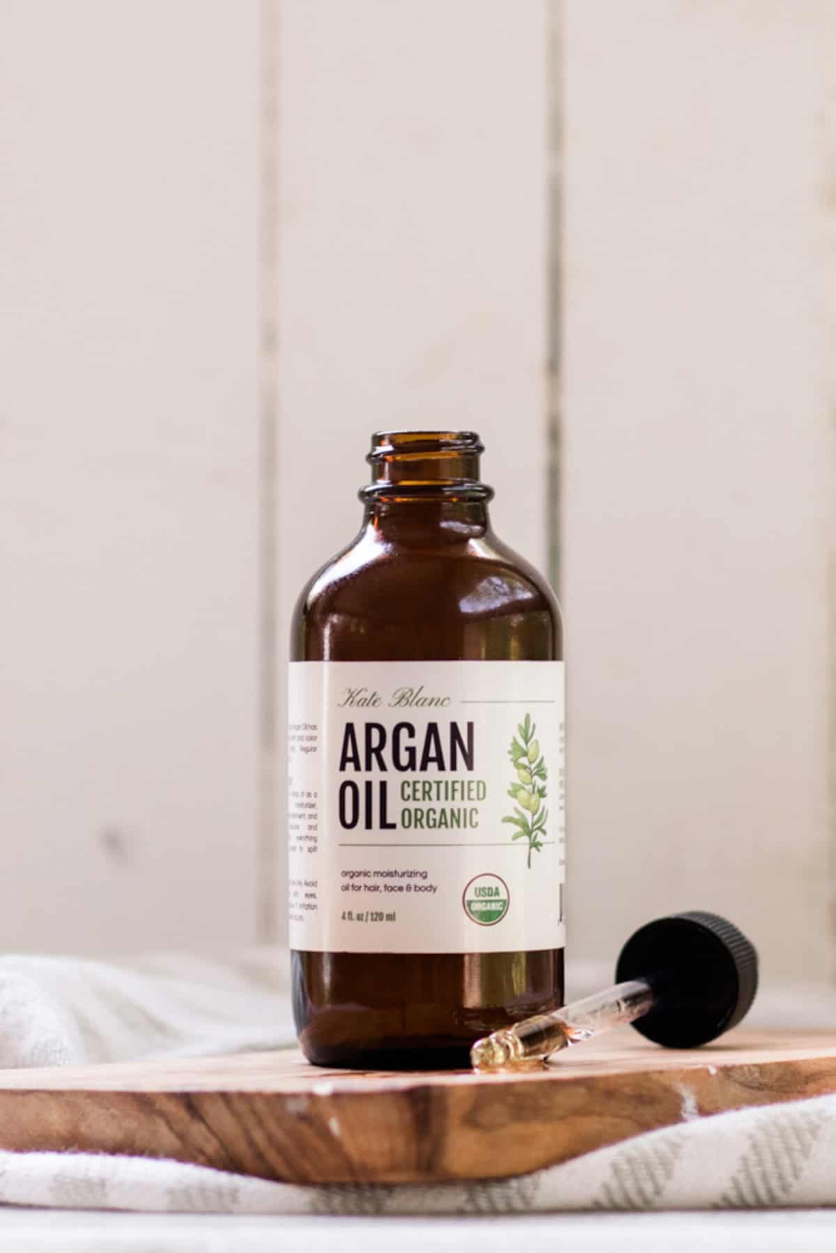 Bottle of argan oil on a wooden shelf.