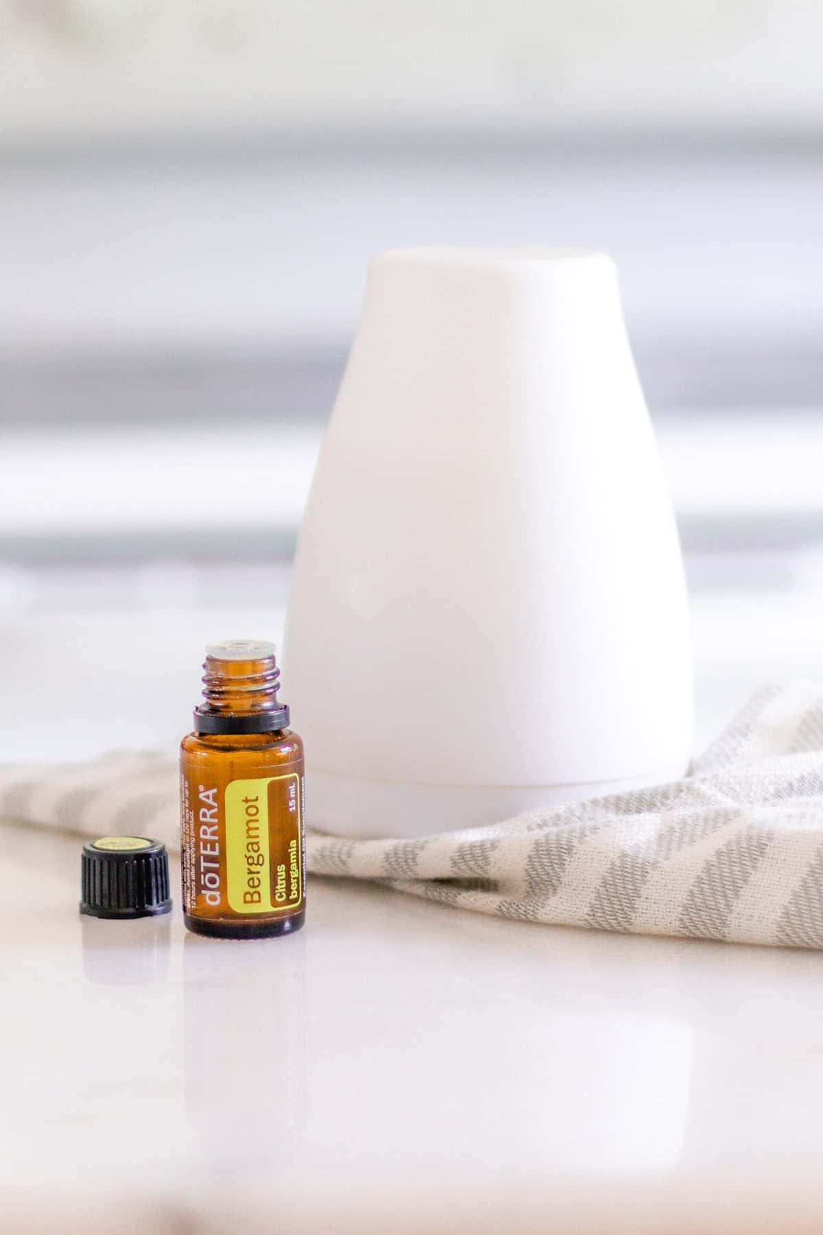 Bergamot oil and white diffuser on white marble.