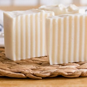 Two cold process shampoo bars standing upright on a wicker mat.