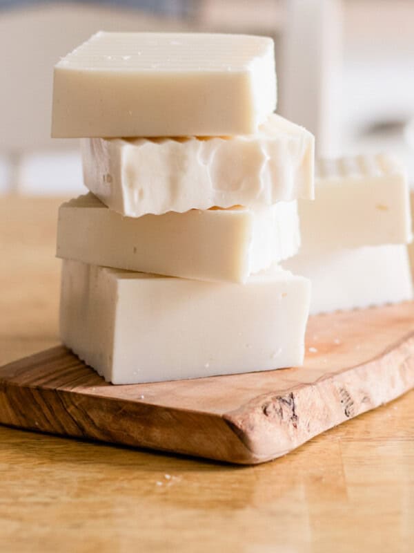 A stack of cold-process shampoo bars on a wooden cutting board.