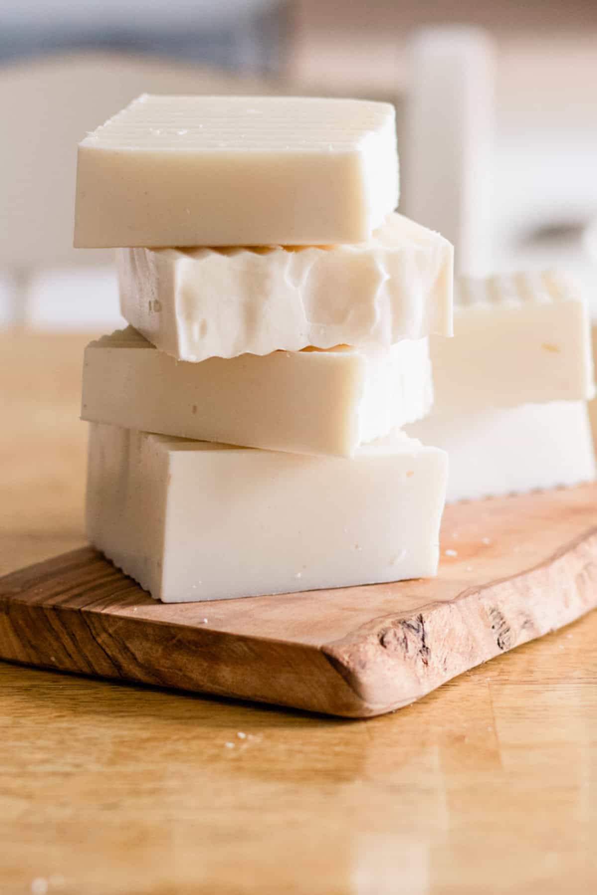 A stack of cold-process shampoo bars on a wooden cutting board.