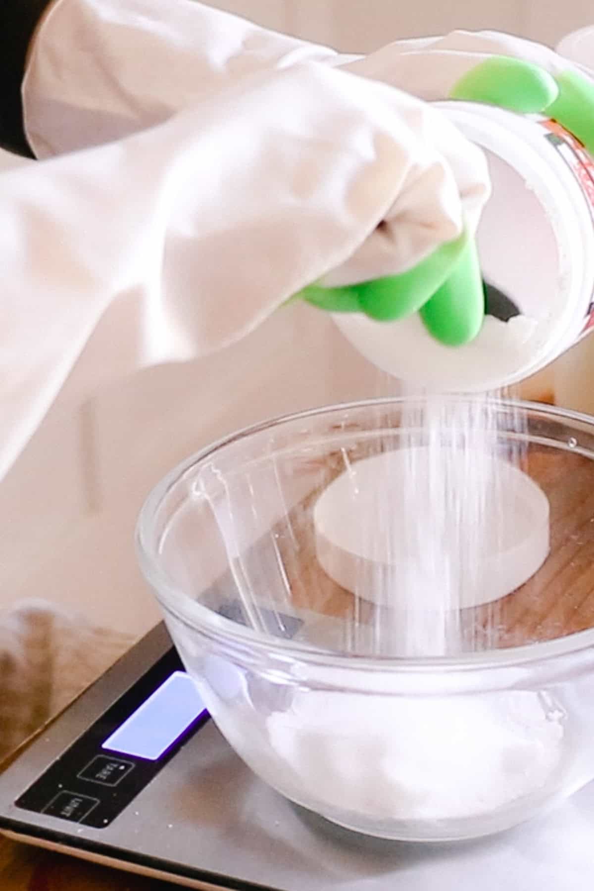 Measuring lye into a glass bowl using a kitchen scale.