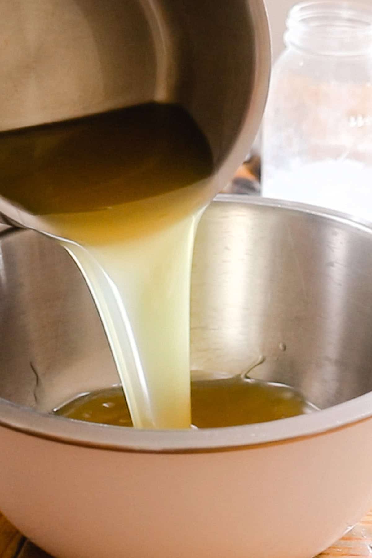 Pouring melted fats from a saucepan to a metal bowl.