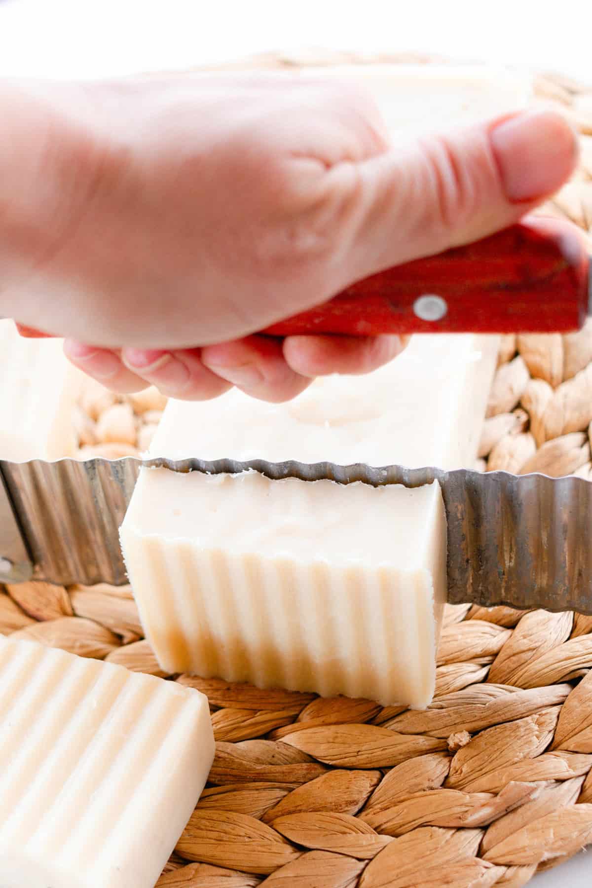 Cutting a loaf of soap into smaller bars with a crinkle-cut soap cutter.
