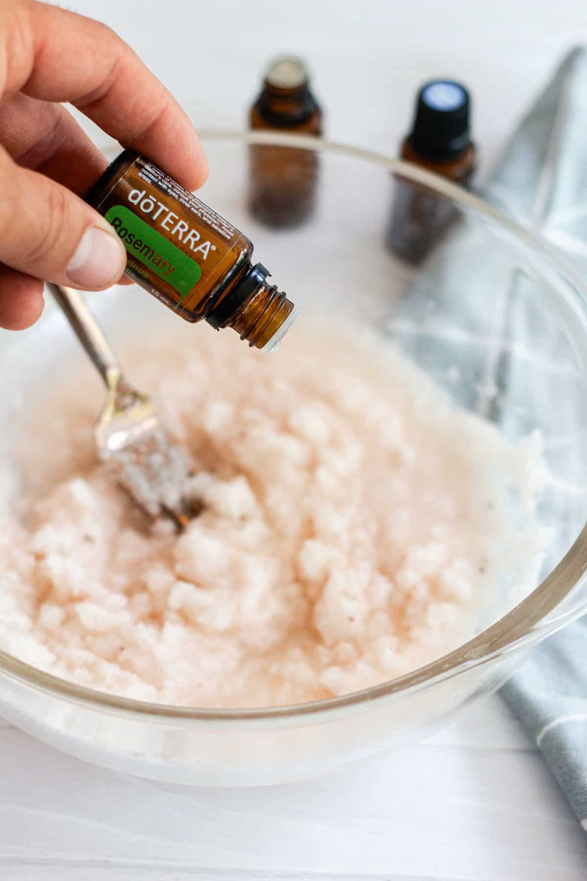 Adding essential oils for the foot bath mixture in a glass bowl.