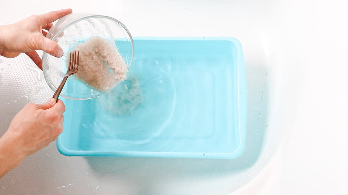 Pouring the detox bath salt mixture into a basin with water for a foot bath.