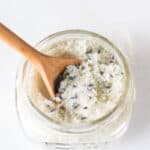 A jar of detoxifying foot bath with a wooden spoon sticking out of it.